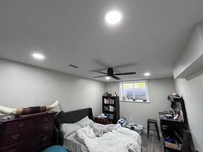 A bedroom with a bed , dresser , desk and ceiling fan.