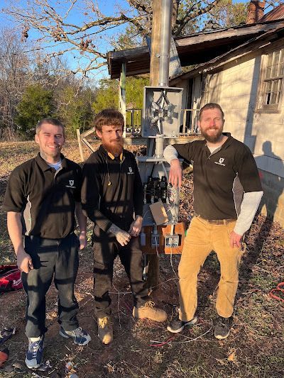 Three men are standing next to each other in front of a house.