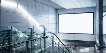 Architectural Metalwork A subway station with an escalator and a billboard on the wall.