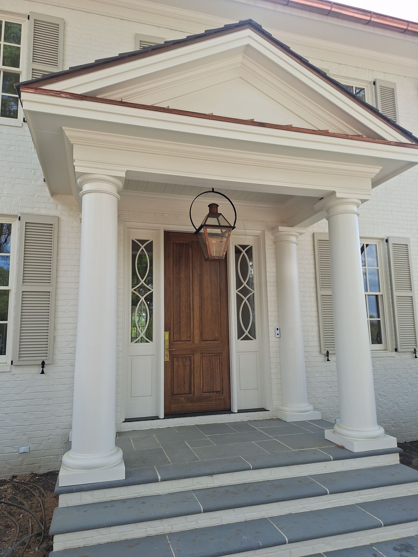 White round Tuscan columns with square plinth bases supporting a pedimented front entry portico