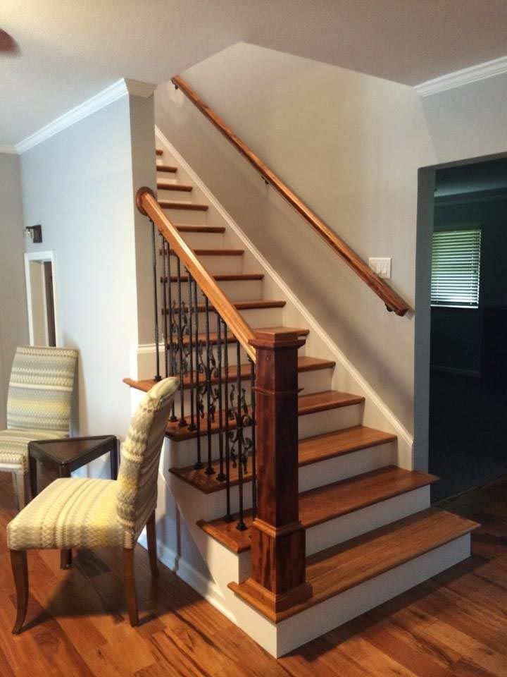 Wooden staircase with wood railing, black iron balusters, and white risers.