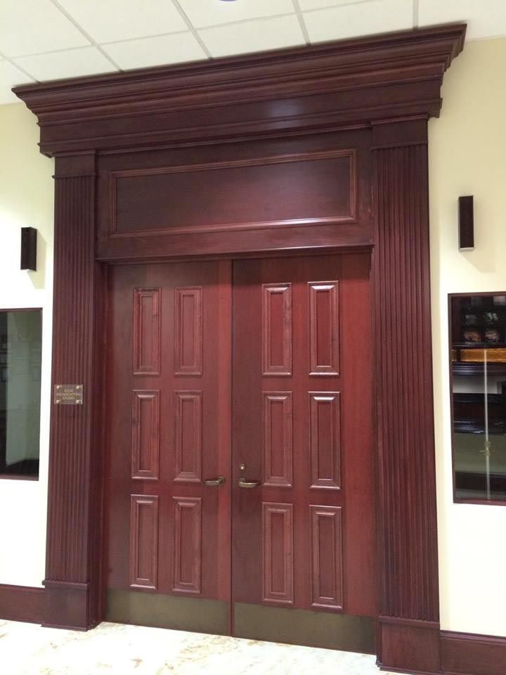 Double wooden doors with dark red stain, framed in matching trim.