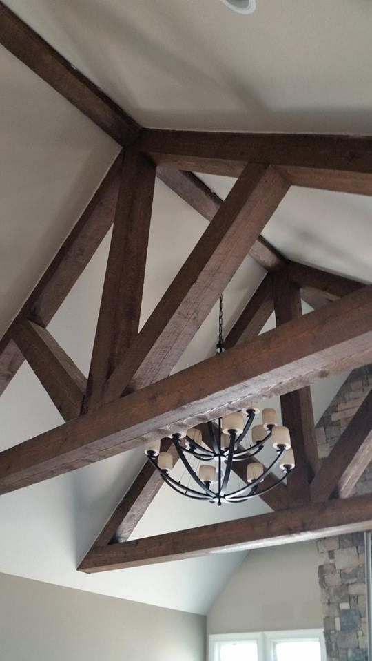 Wooden beams and chandelier in a vaulted ceiling. Brown beams create a truss design.