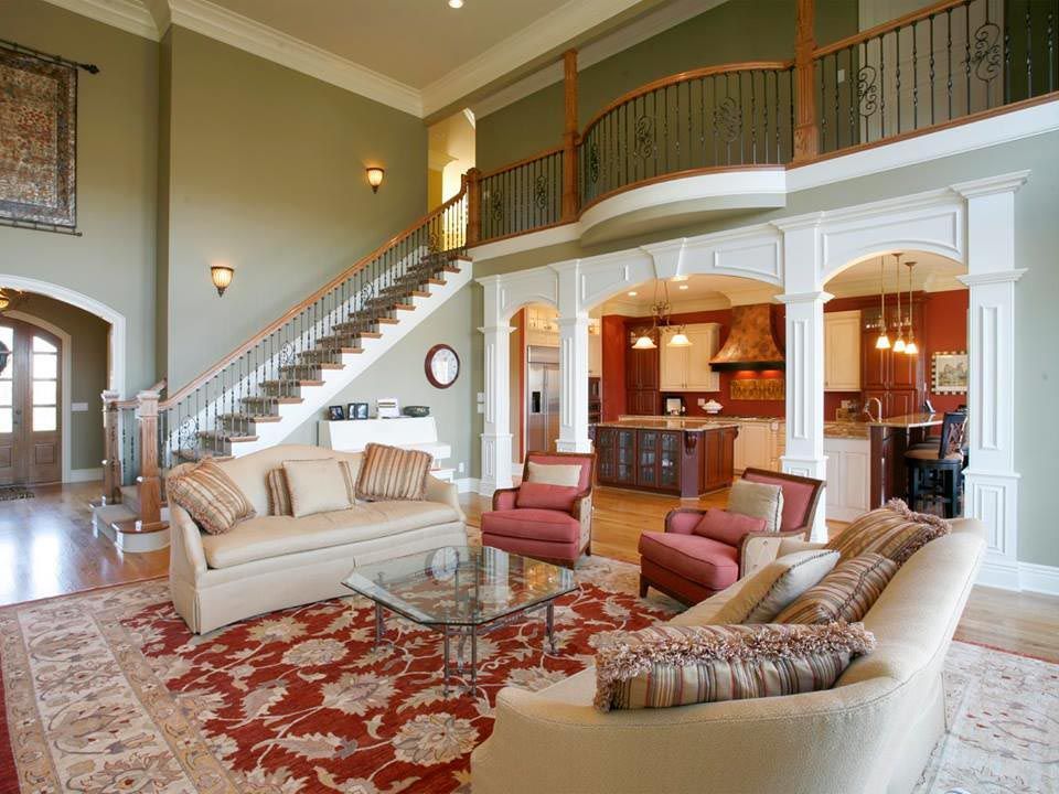 Spacious living room with staircase, red rug, couches, and view into kitchen.