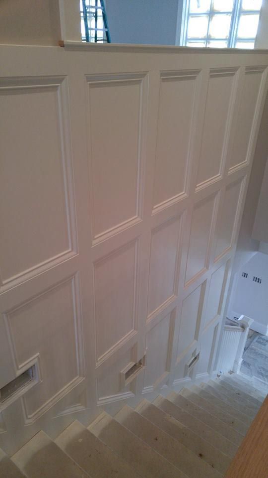 White paneled wall with a staircase descending.