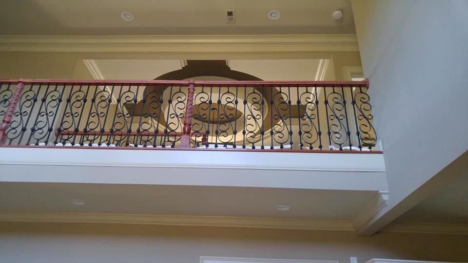 A decorative black and gold metal railing on a balcony inside a building.