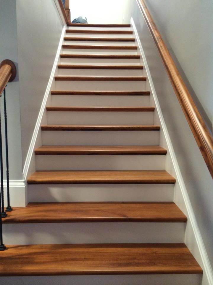 Wooden staircase with white trim and a wooden handrail on the right side.