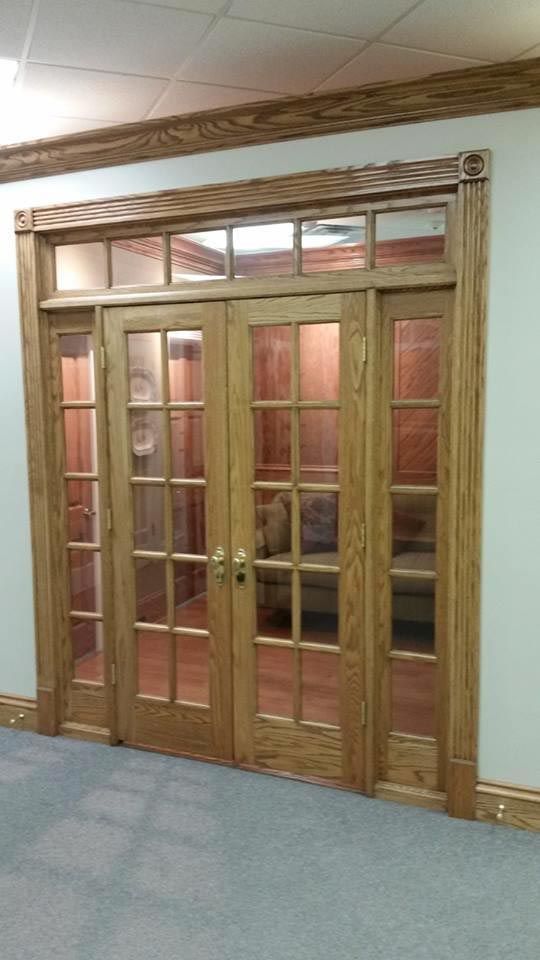 Wooden double doors with glass panels and sidelights in a hallway.