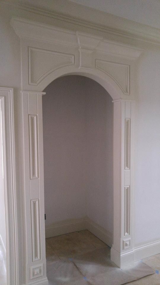 White arched doorway with decorative molding and trim.
