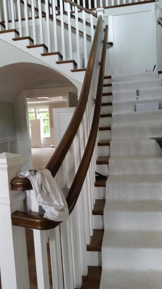 Staircase with white balusters, brown handrail and steps, leading up to an open landing.