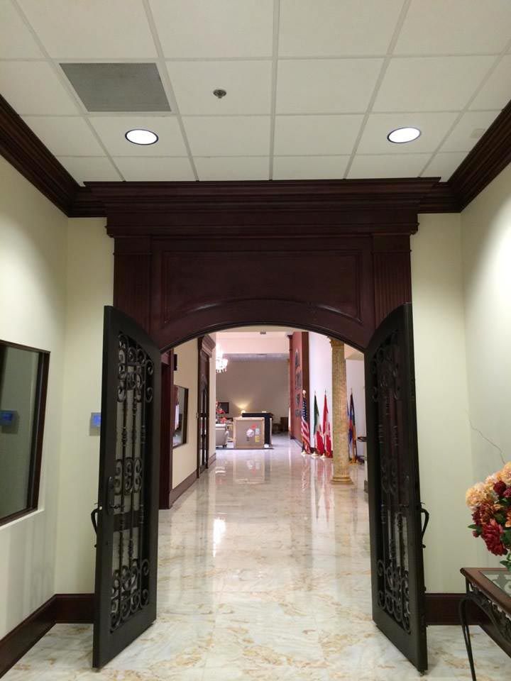 Open double doors with ironwork lead to a hallway with a marble floor and flags.
