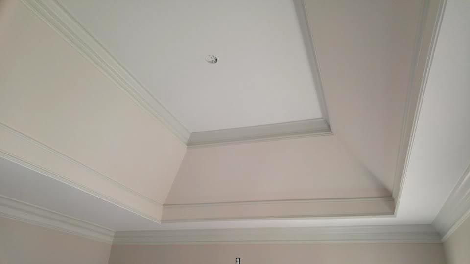 Beige and white angled ceiling with crown molding and recessed central section.