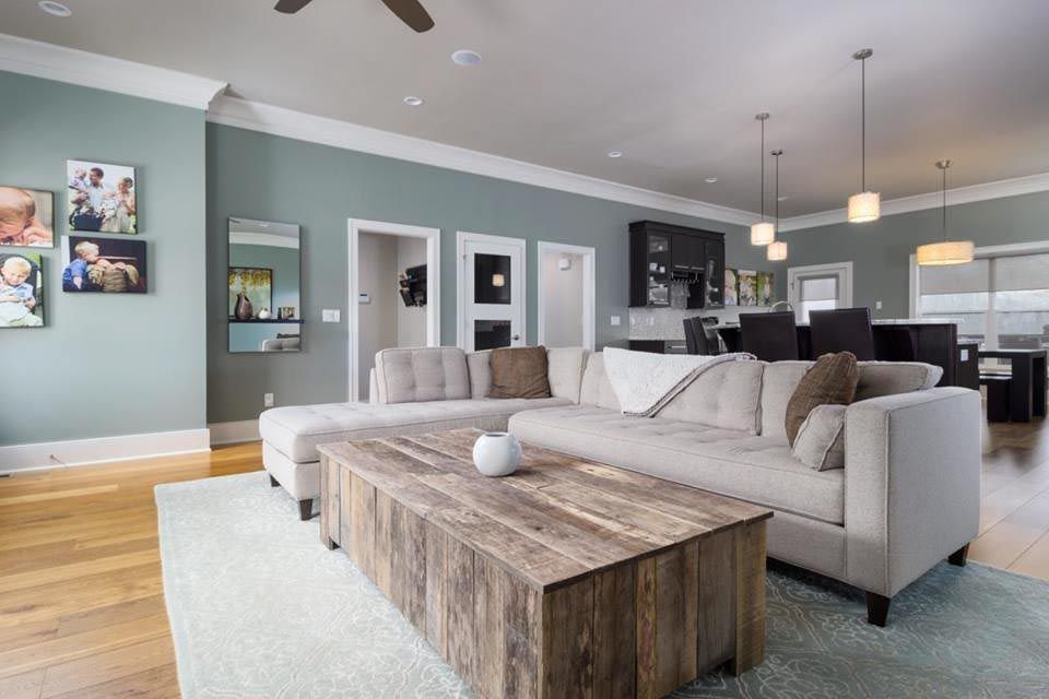 Living room with light-colored couch, wooden coffee table, and teal walls.