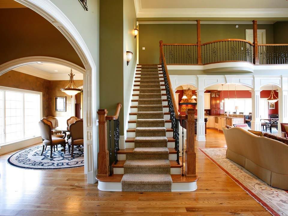 Grand foyer with staircase, hardwood floors, and access to living and dining areas.