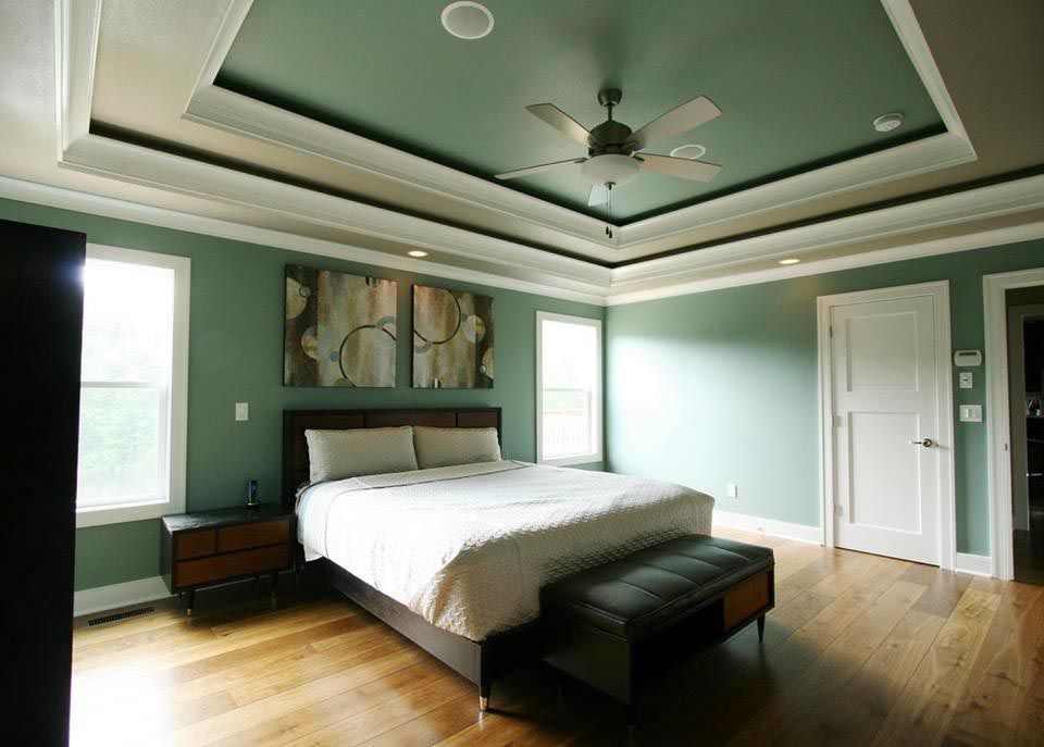 Bedroom with a bed, bench, hardwood floors, and green walls. Ceiling is also green, with white trim.