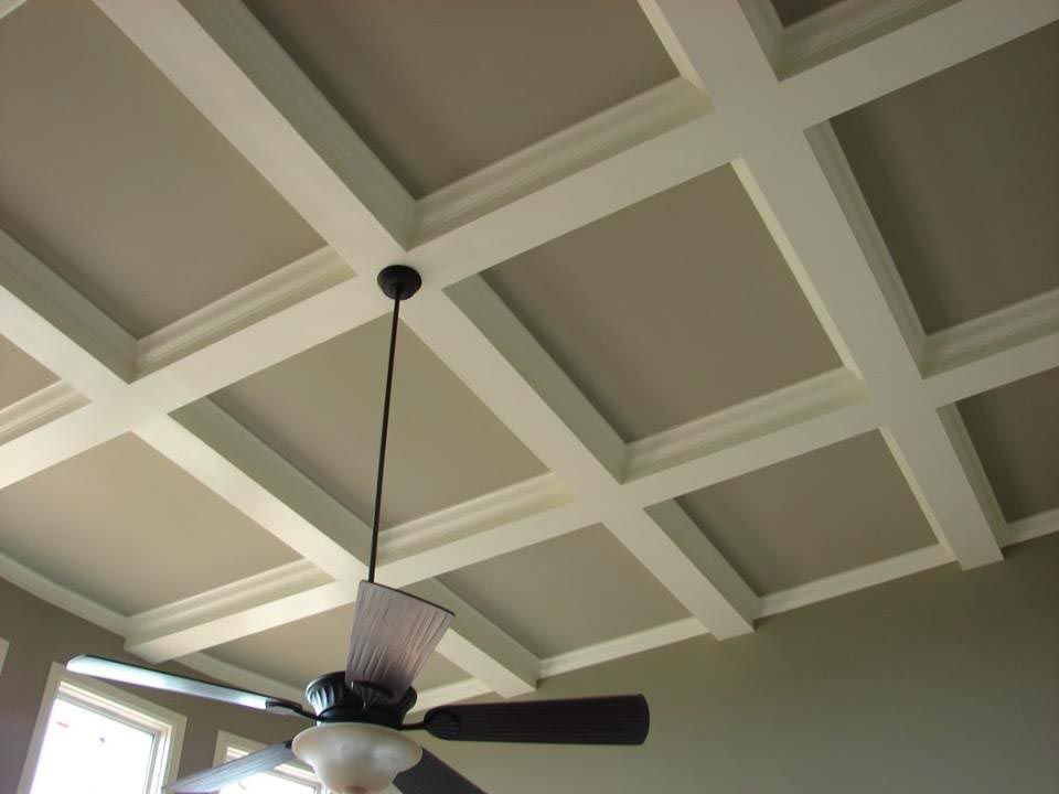 Beige coffered ceiling with white beams, a ceiling fan hangs below.