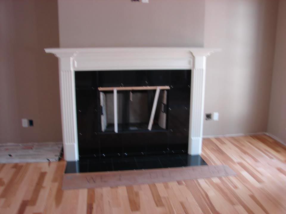 White-trimmed fireplace with a black interior. Light brown walls and wooden floor.