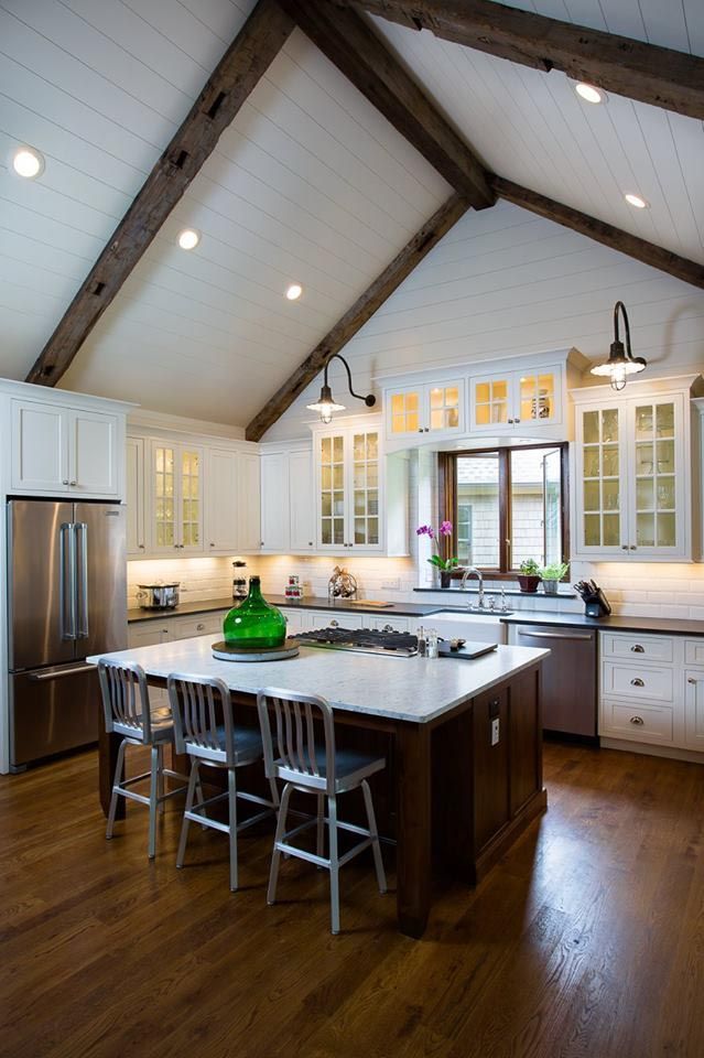 Kitchen with white cabinets, dark wood island, wood floor, and exposed ceiling beams.
