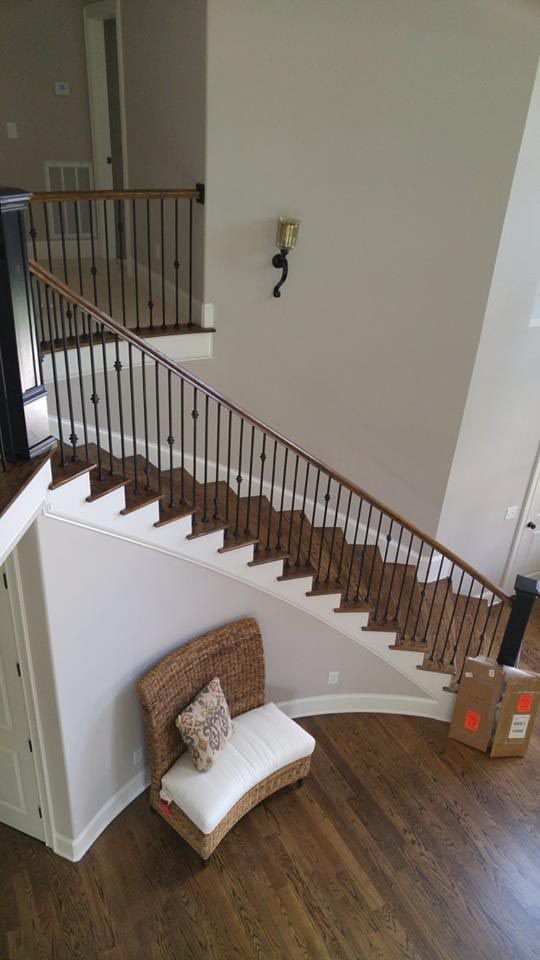 Staircase with wood and black metal railings. A white bench with a pillow sits below.