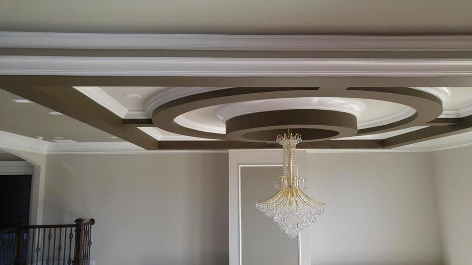 Ornate ceiling with chandelier, rectangular and circular shapes, gray and white colors.