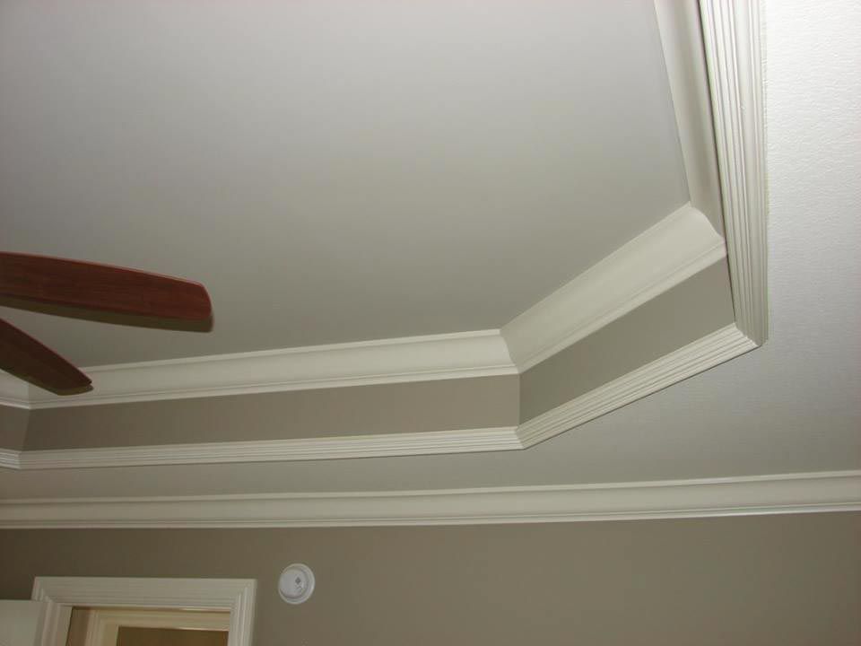 Ceiling with white crown molding and recessed section; beige walls and fan blade visible.