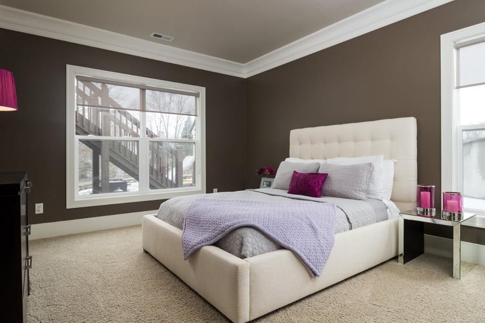 Bedroom with a bed, purple accents, brown walls, and large windows.