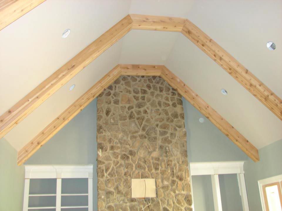 Stone fireplace with light wood beams in a vaulted, off-white ceiling.