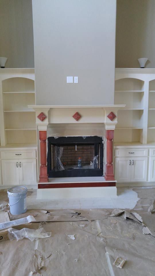 Fireplace with built-in bookshelves. Red accents on mantle and columns. Incomplete construction setting.