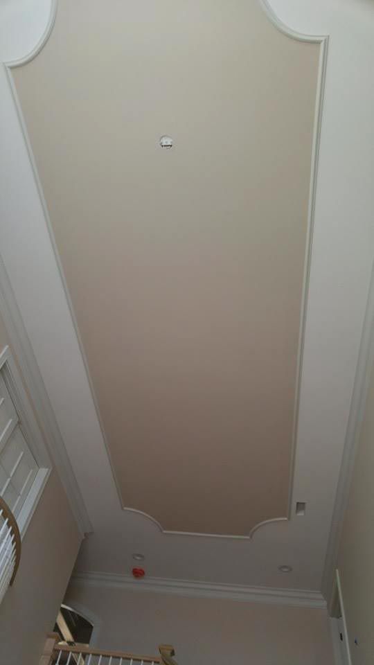 Beige ceiling with decorative molding and recessed section containing a smoke detector.