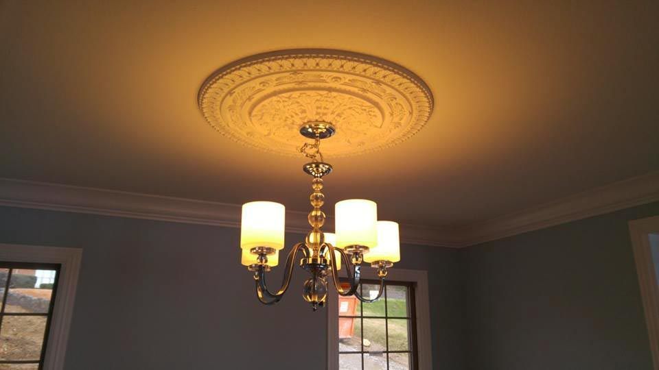 Chandelier hanging from a decorative ceiling medallion in a room with light blue walls.