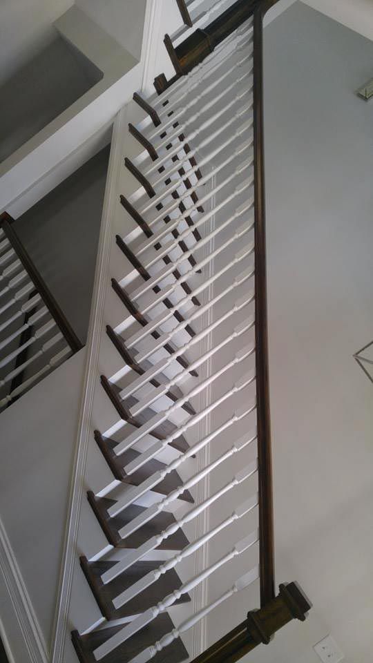 White and brown staircase with angled balusters and a dark handrail.