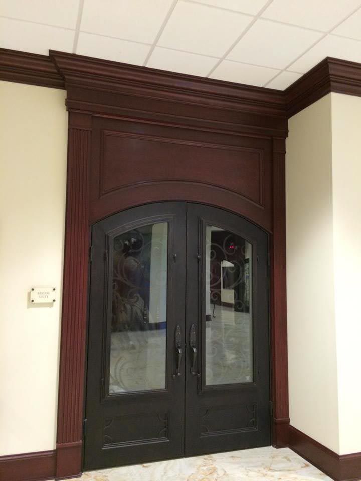 Dark double doors with arched tops, glass panes, and dark wood trim. Beige walls.