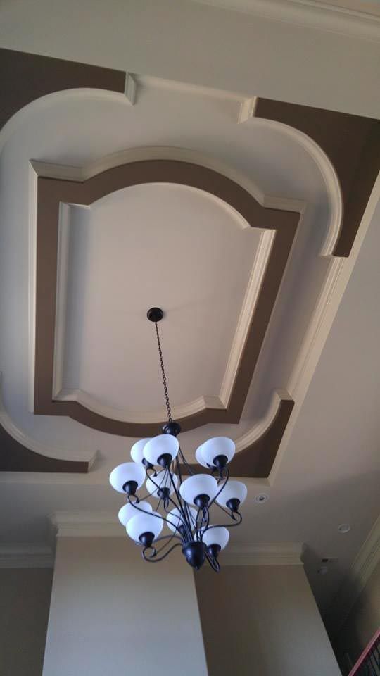 Chandelier hanging from a white ceiling with a decorative brown and white design.