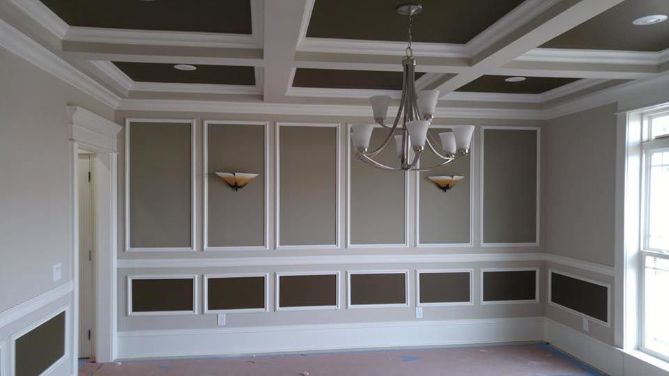 Empty room with decorative wall paneling and a coffered ceiling.