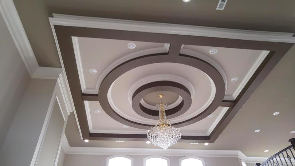 Ornate ceiling design with brown and white trim, recessed lighting, and a chandelier.