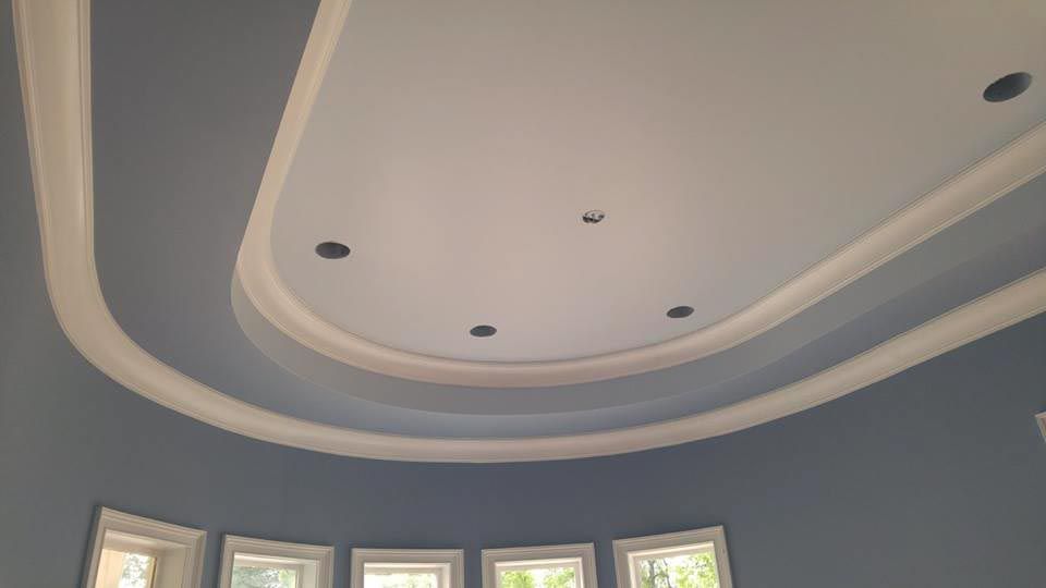 Blue and white room ceiling with curved crown molding and recessed lighting.