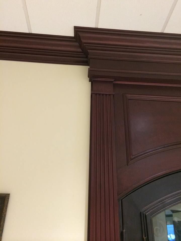 Dark wood trim on a light beige wall. A cabinet corner with fluted details and molding.