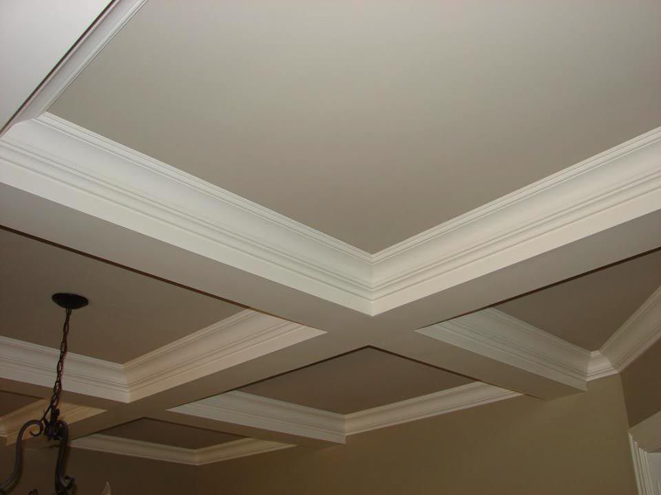 White coffered ceiling with crown molding and recessed panels; a light fixture hangs.