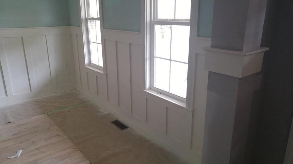 White wainscoting and trim in a room with two windows and light blue walls.
