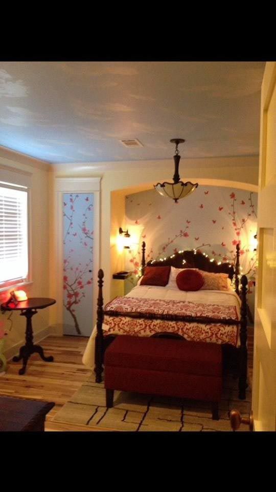 Bedroom with floral wall accents, four-poster bed, and ambient lighting.