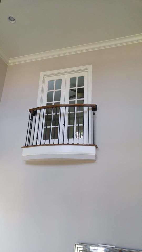 Balcony with white doors and black railing on a beige wall, cream trim.
