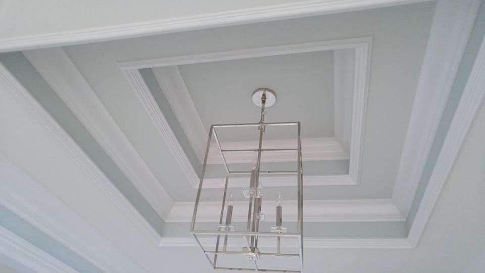 Ceiling with a multi-layered design and a silver chandelier.