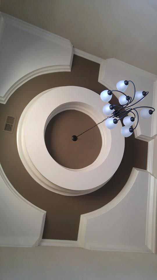 Ceiling with circular recessed design in brown and white, modern chandelier.