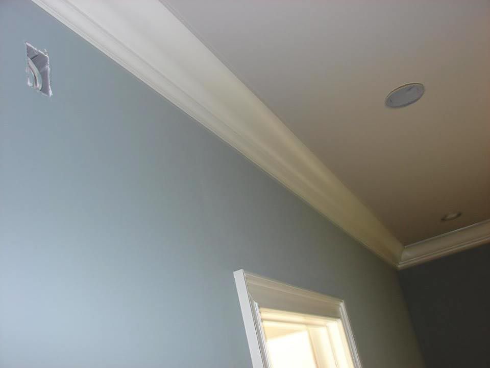 Blue wall with white crown molding, a window frame, and a recessed ceiling light.