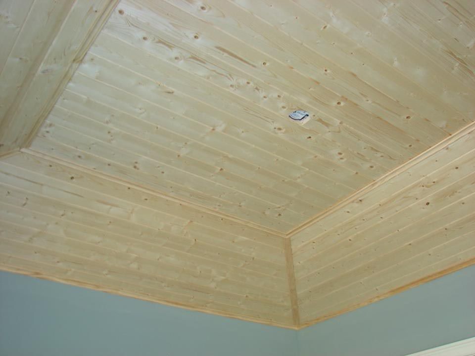 Wooden ceiling with recessed lighting and corner molding; light wood tone.