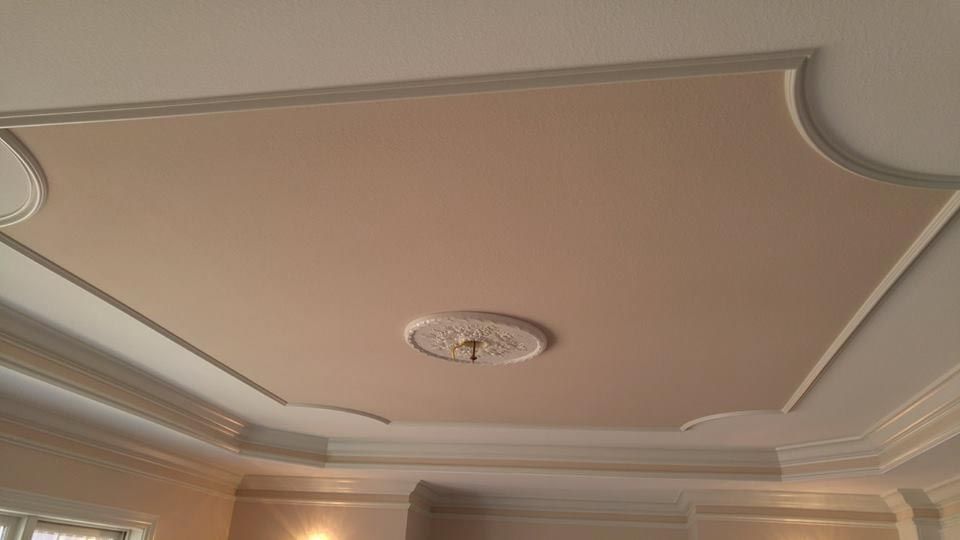 Beige ceiling with recessed square design, ornate molding, and a central light fixture.