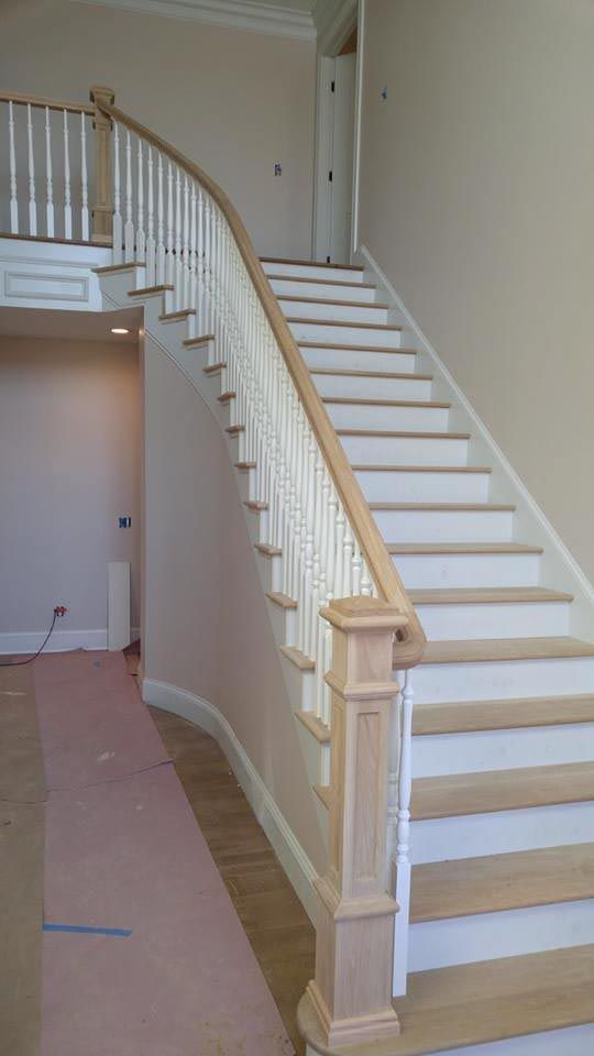 Wooden staircase with white risers and tan treads, banister, and newel posts in a residential interior.