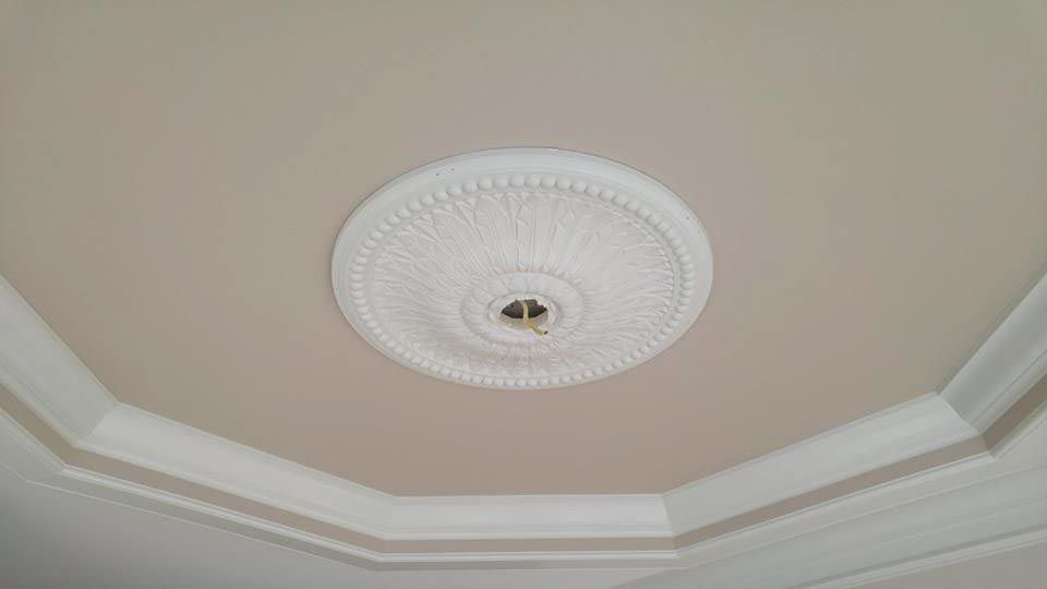 White ceiling with decorative molding and circular light fixture.