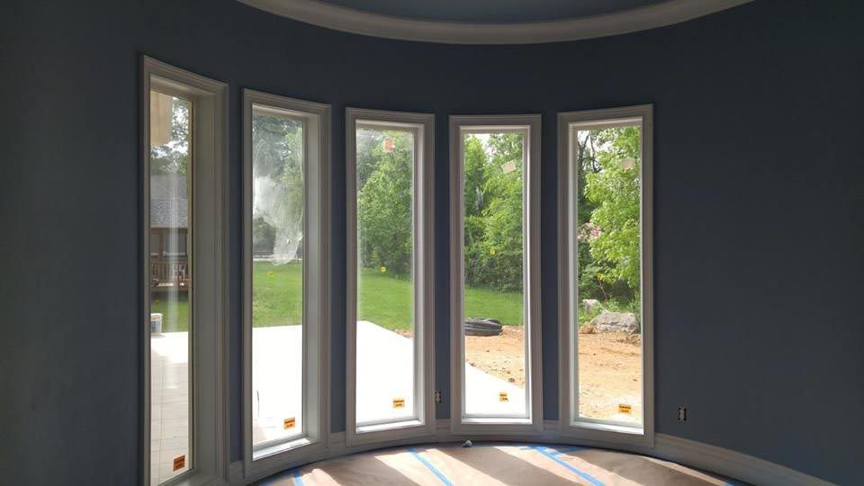 Curved windows in a room with blue walls, looking out onto a green yard.