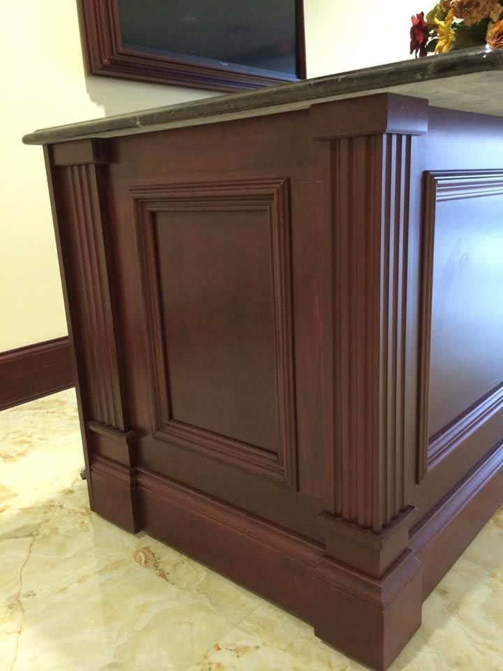 Dark wood cabinet with gray countertop and fluted details.